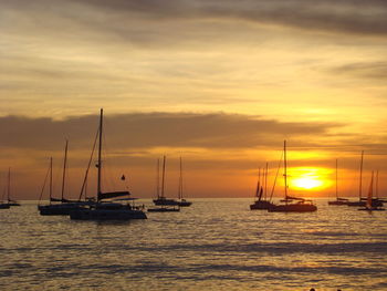 Sailboats sailing on sea against sky during sunset