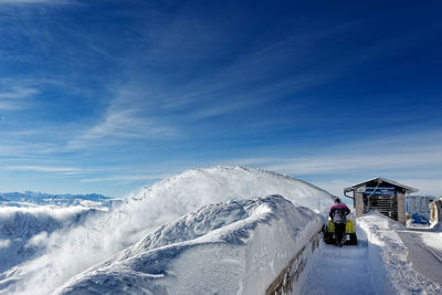 Rear view of man walking on snow field against sky