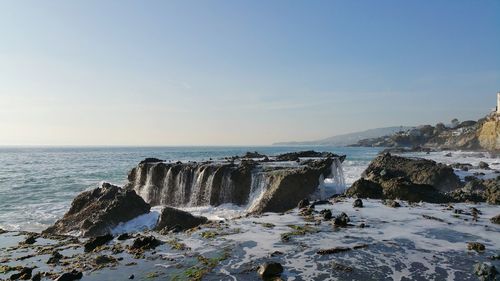 Rock formation in sea against clear sky