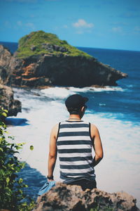 Rear view of man looking at sea against sky