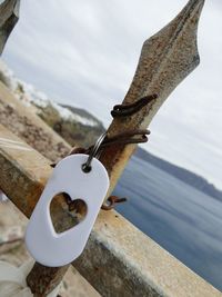 Close-up of rusty metal hanging against sky