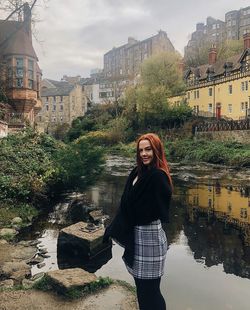 Portrait of smiling young woman standing against buildings