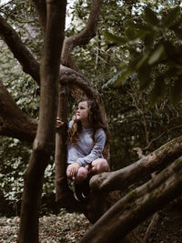 Girl sitting on tree in forest