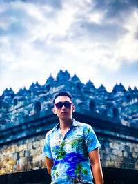 Young man wearing sunglasses standing against sky