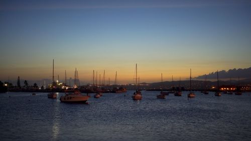 Sailboats moored on river against sky during sunset