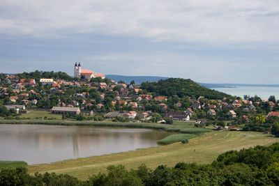 Scenic view of river by cityscape against sky