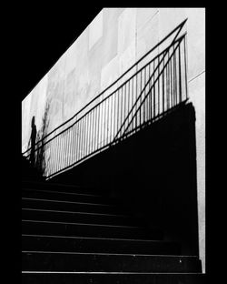 Steps by shadow of railing on wall at night