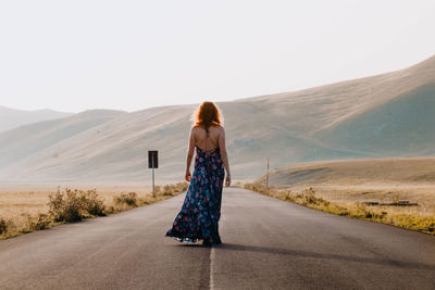 Rear view of woman on road against mountain