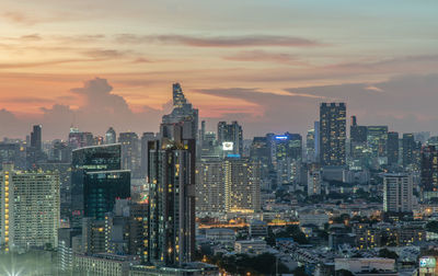 Illuminated buildings in city against sky during sunset