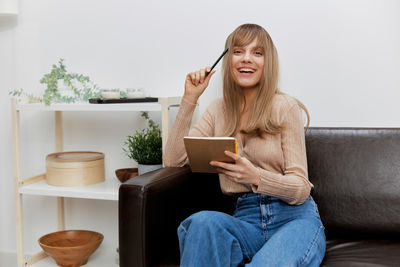 Young woman using digital tablet while sitting at home