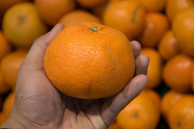 Close-up of hand holding orange for sale at market