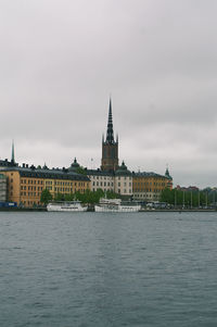 Buildings at waterfront against cloudy sky