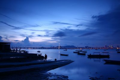 Boats in sea against sky at twilight