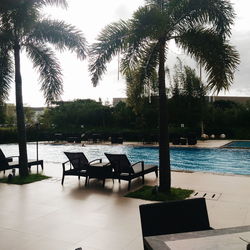 Chairs and table by swimming pool against sky