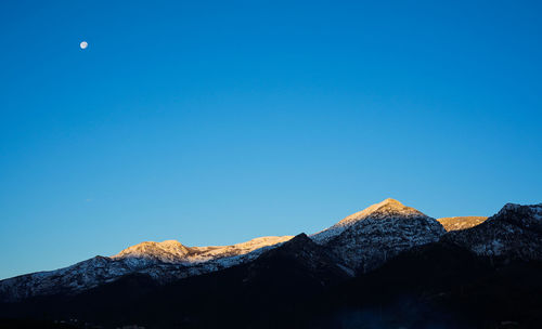 Scenic view of snowcapped mountains against clear blue sky