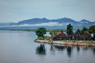 Scenic view of river by buildings against sky