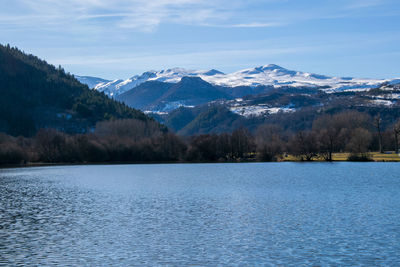 Scenic view of lake by snowcapped mountains against sky