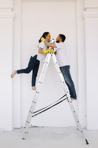 A young couple in love have moved into a new house and are making repairs painting white walls