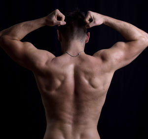 Rear view of shirtless man against black background