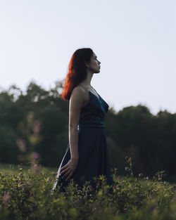 Portrait of young woman standing against plants