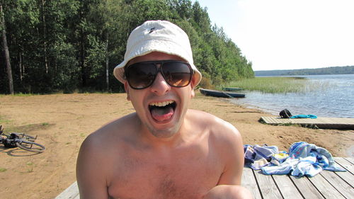 Portrait of man wearing sunglasses on pier at lakeshore