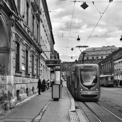 Train on railroad tracks in city against sky