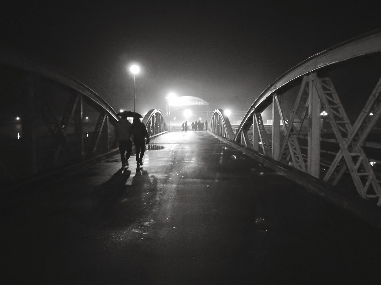 night, illuminated, the way forward, transportation, walking, real people, men, full length, built structure, lifestyles, outdoors, architecture, city, one person, sky, people