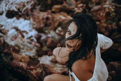 High angle portrait of beautiful woman crouching on rocks