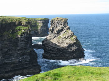 Scenic view of cliff by sea against sky