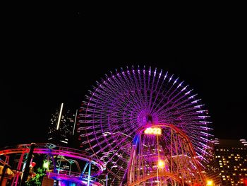 Low angle view of illuminated ferris wheel against sky at night