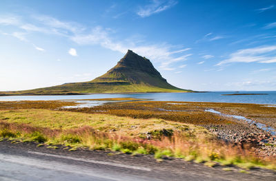 Scenic view of sea by mountain against sky