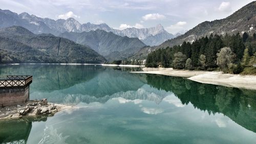 Scenic view of lake by mountains with reflection against cloudy sky