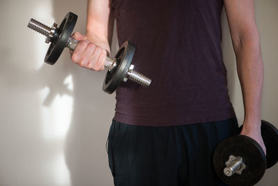 Midsection of man exercising with dumbbells