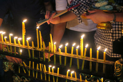 Low angle view of person holding illuminated candles at temple
