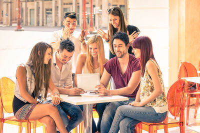 Young woman using mobile phone while sitting on table