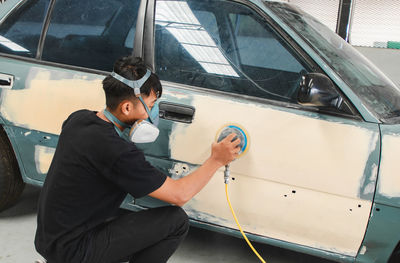 Mechanic wearing mask working on car at garage