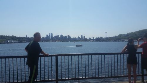 Rear view of man standing by railing against sea