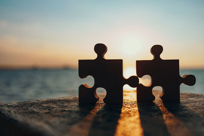 Close-up of friends on sea shore against sky during sunset