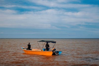 People on boat in sea against sky