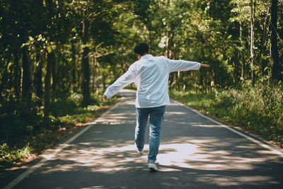 Rear view of man walking on road amidst trees