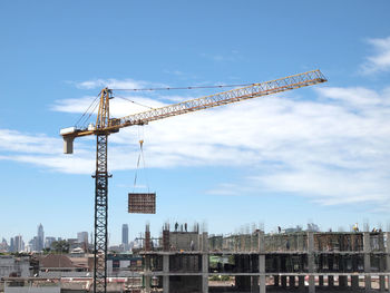 Cranes on construction site against sky in city