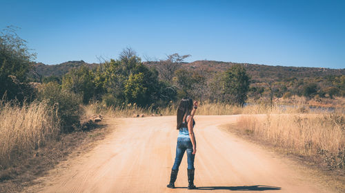 Rear view of woman standing on dirt road