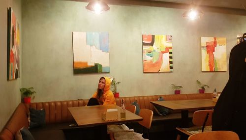 Woman sitting on table in illuminated restaurant