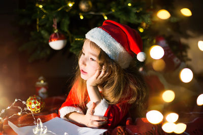 Cute girl lying down by illuminated christmas tree