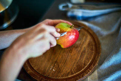 Cropped hands of woman cutting apple at home