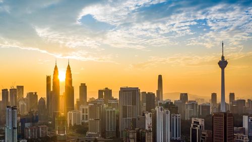 Modern buildings in city against sky during sunset