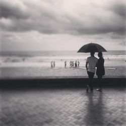 People on beach against cloudy sky