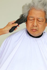 Close-up portrait of man holding cigarette over white background