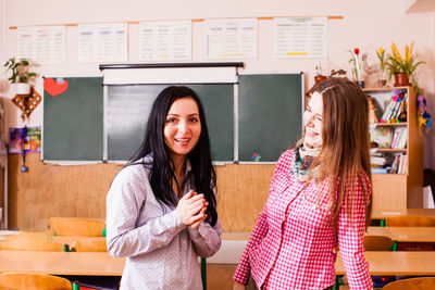 Smiling female teacher standing in classroom