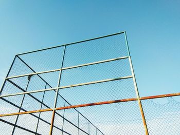 Low angle view of chainlink fence against clear blue sky